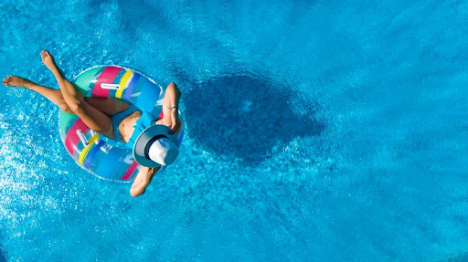 žena v klobúku relaxujúca na nafukovačke v bazéne