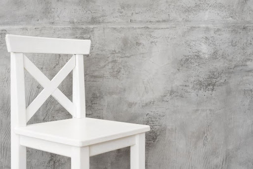biela stolička pri betónovej stene