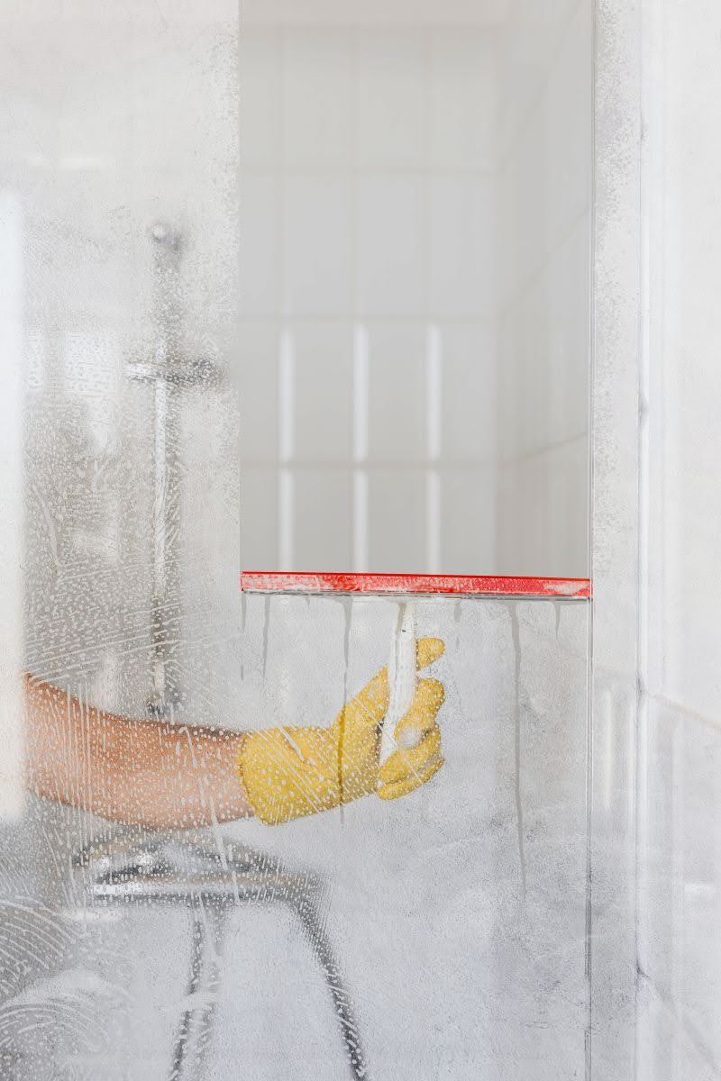 čistenie sklenených dverí na sprchovom kúte stierkou na sklo