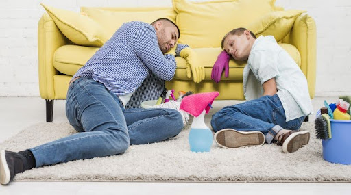 otec so synom s pomôckami na upratovanie zaspali hlavami na gauči